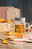 Tee mit Strohhalm im Henkelbecher dazu Kürbisplätzchen mit Zimt und Nüssen