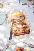 Ofengegrillte Schweinekoteletts mit Rosmarin in der Reine auf sommerlichem Tisch im Freien