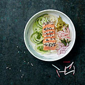 Two sesame salmon sashimi with spaghetti of zucchini, gherkin, onion and pink radish