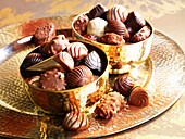 Different chocolates in golden bowls