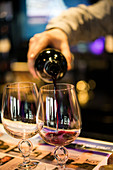 Rotwein wird aus Weinflasche in Weinglas gegossen