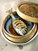 Steamed fish in a bamboo basket