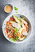 Bowl of poached chicken noodles, avocado and grapefruit
