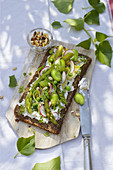 Wholemeal bread slice with green asparagus, broad beans and peas