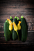 Fresh courgettes and courgette flowers on a wooden background