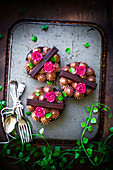 Mini brownie cheesecake decorated with chocolate bars, cream dots and rose petals