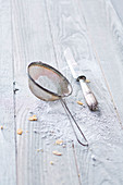 Sieve, icing sugar and a vintage knife on a wooden background