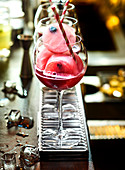 Roter Cocktail mit fruchtigen Beeren-Eiswürfeln