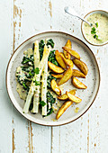 White asparagus on creamed spinach with potato wedges