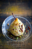 Poached pear sprinkled with crushed pistachios and chocolate flakes