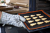 Christmas tree biscuits being taken out of the oven