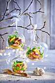 Weihnachtlicher Salat angerichtet in Weihnachtskugeln aus Glas