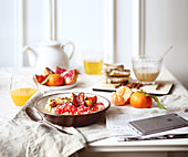 Gedeckter Frühstückstisch mit Müsli, Saft und Früchten