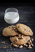 Chocolate -chip cookies and a glass of milk on a black background.