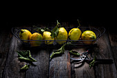 Zitronen in Drahtkorb vor dunklem Hintergrund