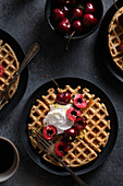 Vegan and gluten free waffles made with oat flour, served with coconut whipped cream, fresh cherries, lemon zest and maple syrup
