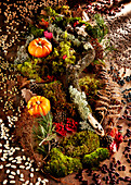 Herbstdekoration aus Moos, Blättern, Kürbissen und Zapfen