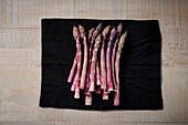 Fresh purple asparagus on black cloth
