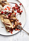 Crepes with strawberries, melted chocolate, and cream