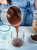 Selbstgemachten Schokoladen-Nuss-Brotaufstrich in Glas füllen