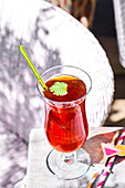 Ice tea peach with grenadine and coriander on an outdoor table