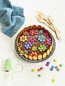Chocolate cake decorated with flowers made of colorful candy coated chocolate candies