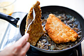 Prepare katsudon: fry breaded cutlets in a pan