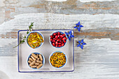 Capsules of food supplements, flower pollen and pomegranate seeds in small bowls