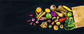 Grocery bag with healthy vegetables and fruits on a black background