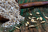 Wooden spoon with oat flakes next to oat grains on wooden background