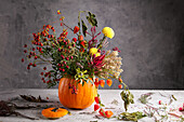Herbstlicher Blumenstrauß für Halloween in ausgehöhltem Kürbis