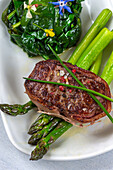 Grilled beef tournedos with spinach and green asparagus
