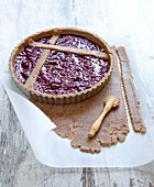 Placing the strips of pastry on the tart in a crisscross pattern