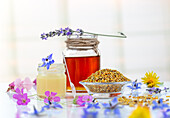 Miel, pollen de fleurs et gélée royale regroupés sur un fond clair parsemé de fleurs.