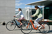 Two young women cycling cross-town, Berlin, Germany