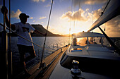 Mann auf einem Segelboot bei Sonnenuntergang, Iles des Saintes, Guadeloupe, Karibik, Amerika