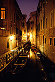 Gondeln in einem beleuchteten Kanal in Venedig, Italien