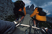 Drei Mountainbiker in den Dolomiten, Italien