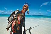 Fischerman with harpoon and diving mask, carrying fish, Sam Lord's Beach, St. Philip, Barbados, Caribbean