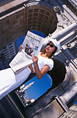 Woman reading newspaper in front of Siegestor, Munich, Bavaria, Germany