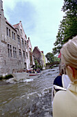 Menschen fahren mit Booten durch die Altstadt von Brügge, Belgien