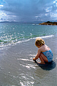 Playing child at water's edge, Sardinia, Italy