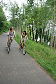 Two women cycling on a cycle path near a lake, Lake Griebnitzsee, Berlin, Germany