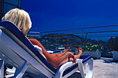 Woman sunbathing on housetop terrace, Hotel Eden, Lisbon, Portugal