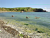 Teenager on floating tires, Lulworth Cove, South England Great Britain