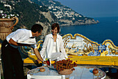 Junge Frau und Kellner auf der sonnigen Terrasse des Hotels San Pietro, Positano, Campania, Italien, Europa