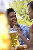 Young couple with beer stein and pretzel in beer garden, Munich, Bavaria
