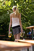 Rear view of woman carrying two beer steins, Munich, Bavaria