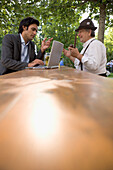 Old Bavarian man and young businessman with laptop in beer garden, Lake Starnberg, Bavaria, Germany