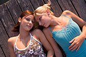 Two young women lying on boardwalk, Munich, Bavaria